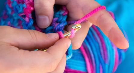 Close up of hands crocheting a blanket.
