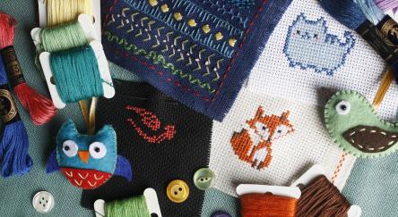 A collection of colorful cross stitch kits and spools of thread arranged neatly on a table.