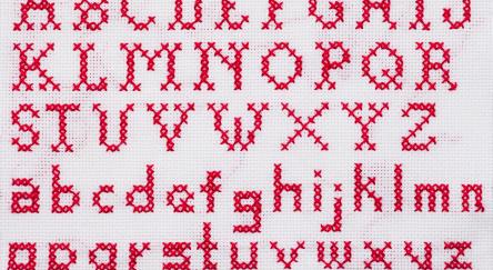 Red Alphabet cross stitch sampler with upper case and lower case letters.