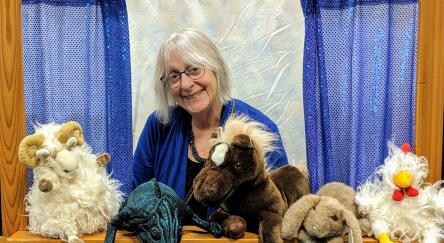 Puppeteer, and master storyteller, Elspeth Bowers poses on a stage with her puppets.