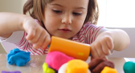 Little girl creating with playdough.