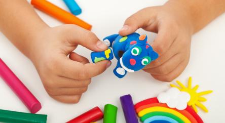 Child playing with colorful clay making animal figures - closeup on hands.