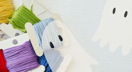 embroidery floss on aida cloth background with two almost transparent ghosts