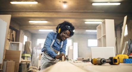 One African-American female carpenter working with wood in her workshop.