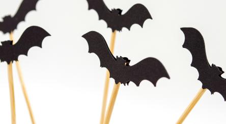 Black bat puppets made from paper and wood sticks.