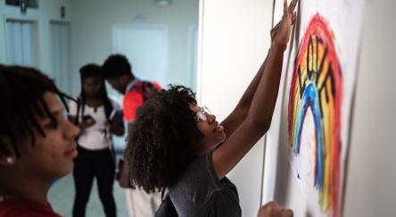 Students taping hand-painted poster to wall.
