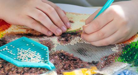 Close up of hands working on a diamond art mosaic project.