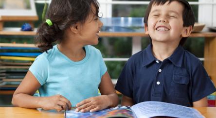 Two delighted kids enjoying a book in a library.