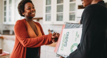A green sustainable energy advisor is shaking hand with a customer at home.