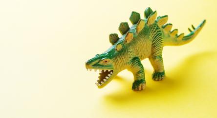 Plastic dinosaur toy on a yellow background.
