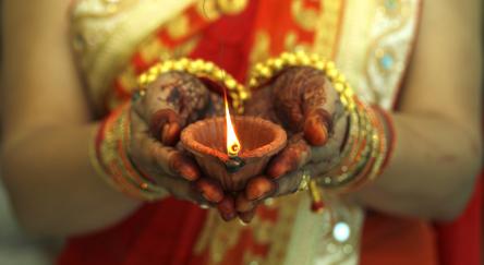 Indian woman holding Diwali oil lamp.