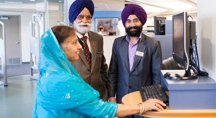 An FVRL staff member helps a Punjabi couple at Muriel Arnason Library.