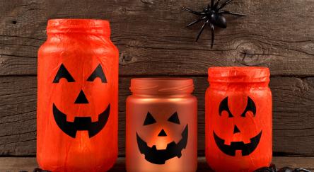 Mason jar Halloween Jack o Lanterns against an old wood background.
