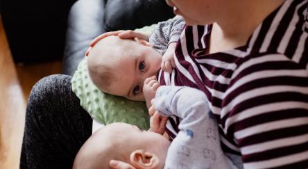 Woman nursing twins on her lap.