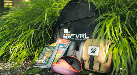 A travel backpack featuring, binoculars, and a map, perfect for exploring nature.