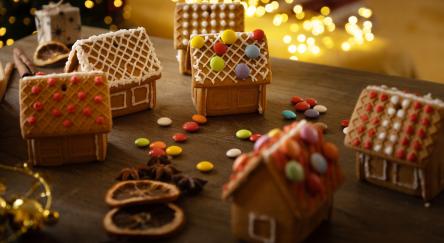 Multiple mini decorated gingerbread houses standing on the table in a cozy Christmas atmosphere.
