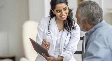 A young female South Asian doctor discusses medical results with a senior South Asian man.