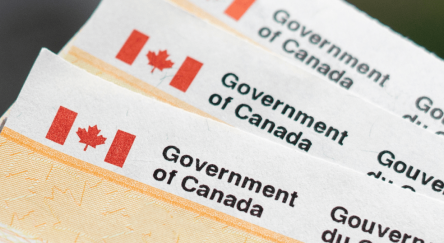 Government of Canada benefit cheques stacked in a pile.