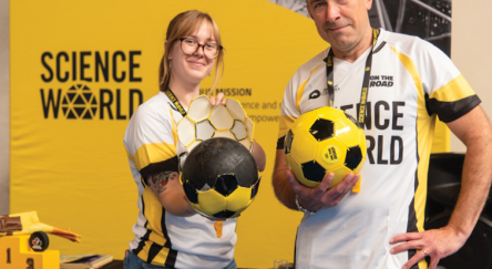 People holding soccer balls in front of Science World backdrop.