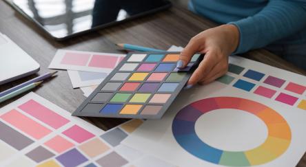 A designer evaluates a color palette, reviewing swatches and color wheels to finalize design choices, showcasing creativity and attention to detail.