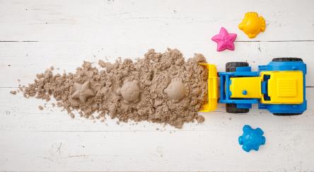 A tractor rakes kinetic sand along with plastic sea animal molds.