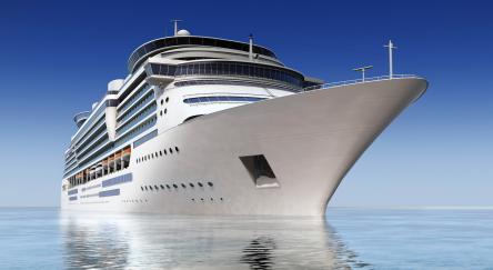 Luxury white cruise ship shot at angle at water level on a clear day.
