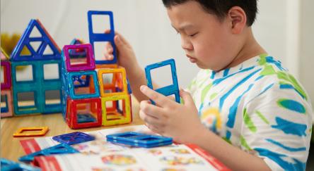 Young boy builds using magnetic Magformer pieces.