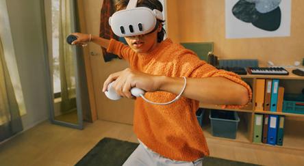 Teen using mixed reality VR headset with controllers.