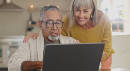 A man and woman looking at a laptop screen.