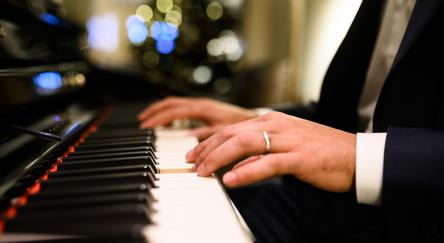 Close-up of a musician's hands playing a digital piano during a Christmas party, creating a festive and musical atmosphere.