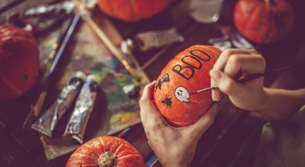 Woman painting on pumpkin for Halloween.