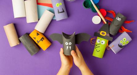 Kid hands holds a Halloween decorative toy from toilet roll.