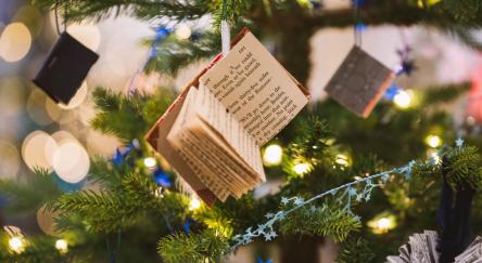 a small open book hangs on a tree that is decorated with lights