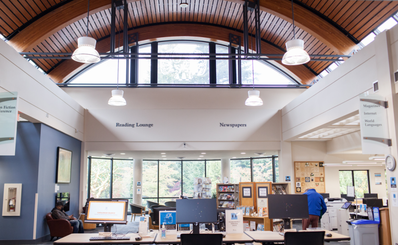 Clearbrook Library's interior showcases a grand ceiling above shelves filled with books, creating an inviting atmosphere.