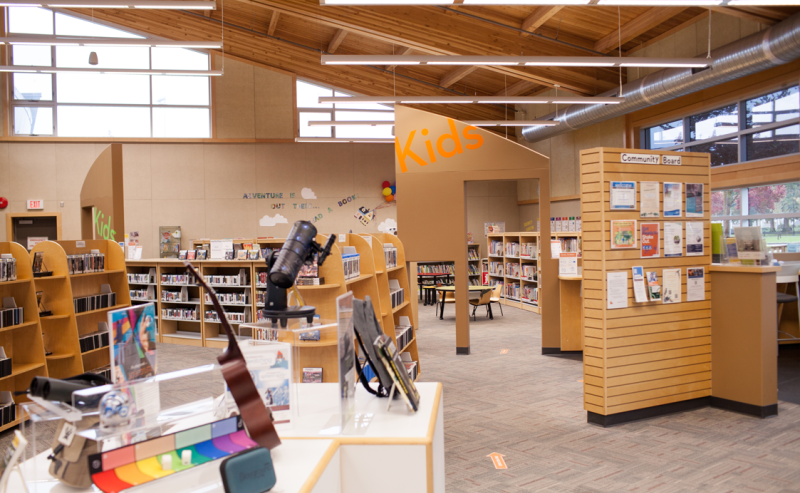 Inside Abbotsford Community Library, a cozy kids' space filled with books and a computer for community access.