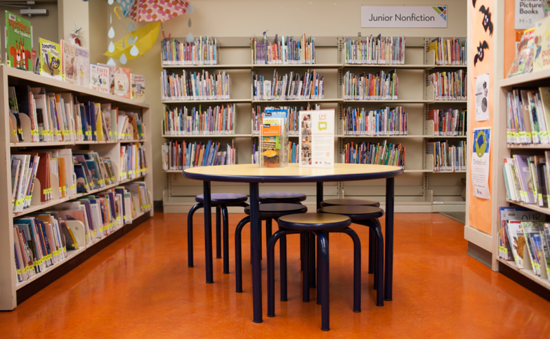 Interior of Aldergrove Library featuring a table and chairs in the children's area surrounded by bookshelves.