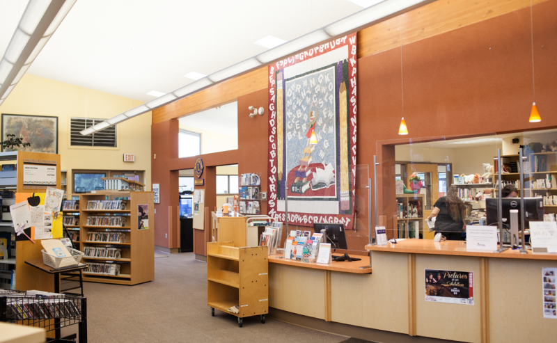 Interior of Agassiz Library featuring a large sign prominently displayed on the wall amidst rows of bookshelves.