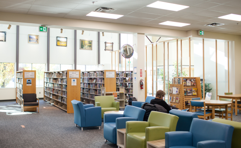 A man enjoys a quiet moment in a chair at the City of Langley Library, surrounded by towering bookshelves.