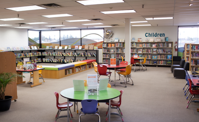  Tsawwassen Library's interior showcasing the children's area and a vast collection of books neatly arranged on shelves for everyone to explore.