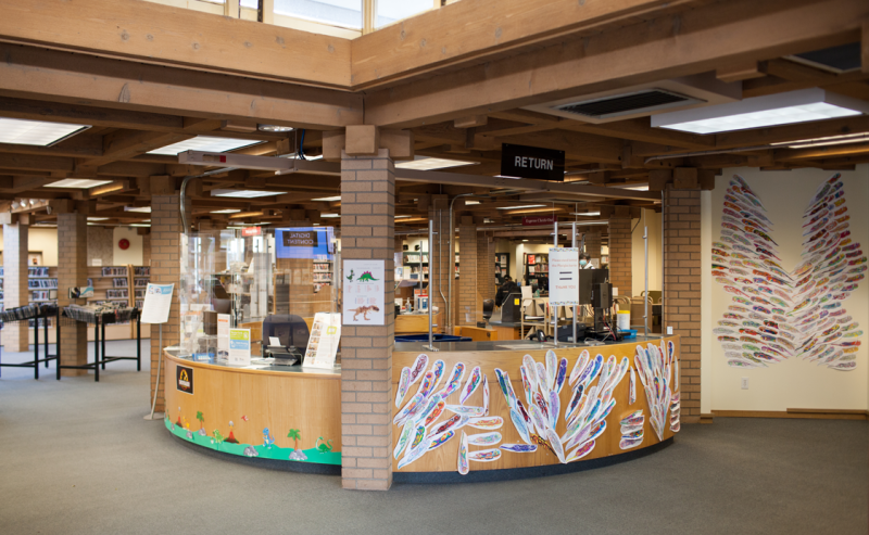 Interior view of Ladner Pioneer Library showcasing the information desk and multiple tables in a bright, open space.