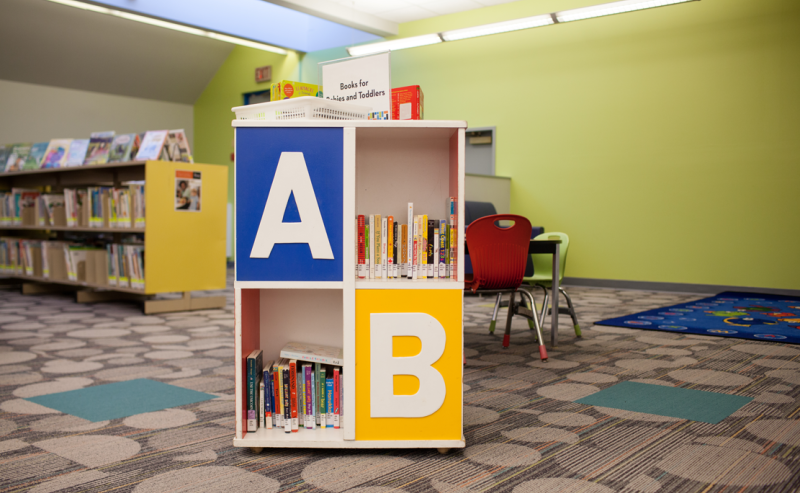 A bookcase filled with various books inside the George Mackie Library, showcasing a cozy reading environment.