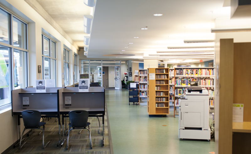 Interior view of the Muriel Arnason Library's long hallway lined with numerous tables for study and reading.