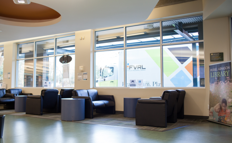 A spacious interior of Muriel Arnason Library featuring rows of chairs and tables for reading and studying.