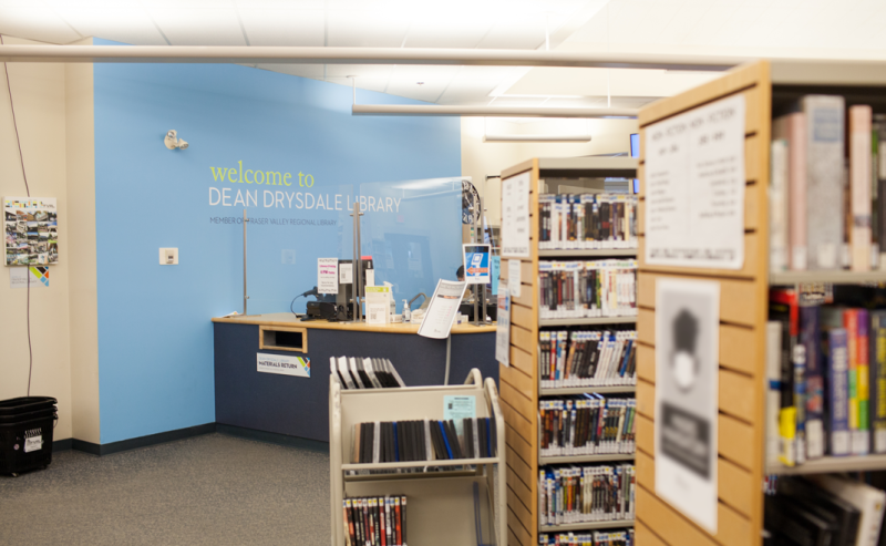 Interior of Dean Drysdale Library featuring shelves of books and a prominent sign indicating the library's name.