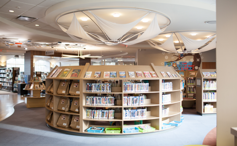  Inside Pitt Meadows Public Library, a circular space with bookshelves surrounding a central round table for community use.