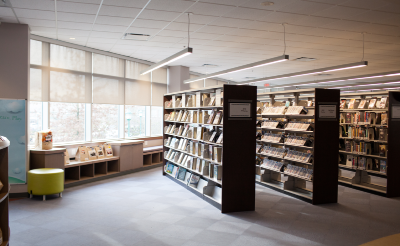  A large library interior at Pitt Meadows Public Library filled with shelves of books and inviting reading spaces.