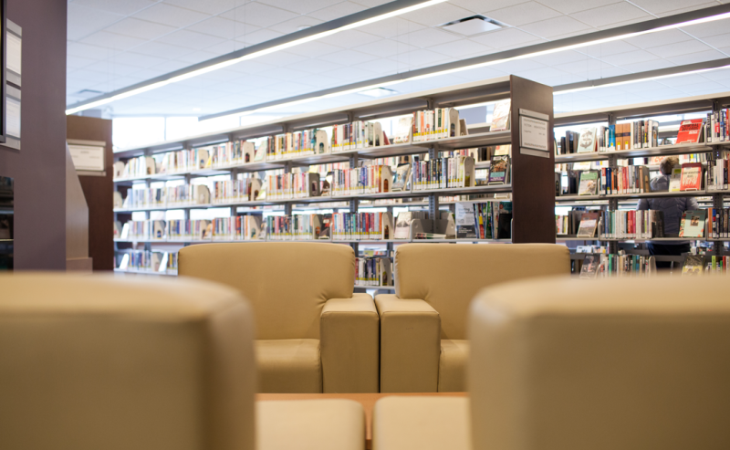  Interior of Pitt Meadows Public Library featuring chairs and bookshelves, creating a cozy reading environment.