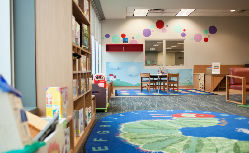 The children's area of Maple Ridge Public Library features a very hungry caterpillar rug on the floor, inviting kids to sit and read.