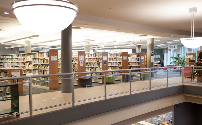Interior view of the second floor of Maple Ridge Public Library featuring multiple bookshelves and ambient light.