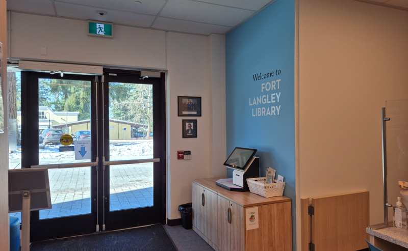 The entrance door of Fort Langley Library, adorned with a sign that offers guidance or directions to patrons.